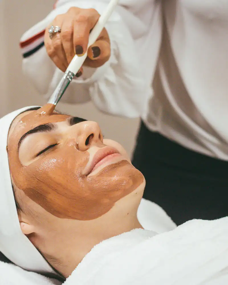 A client relaxing under a clay mask during a facial treatment